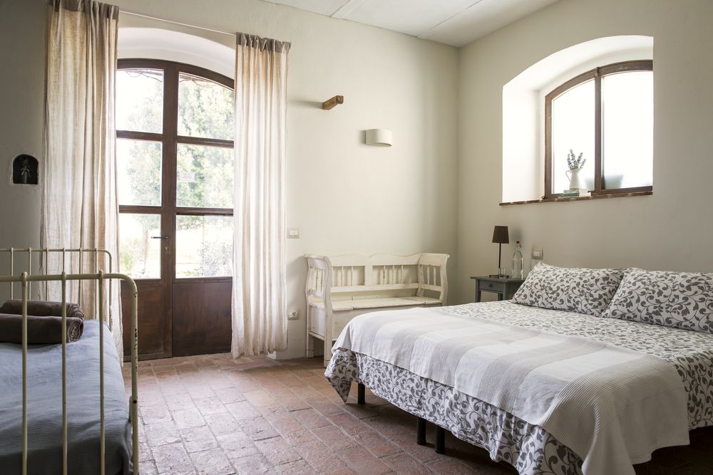 A bedroom with white linen and a deep window looking onto the hills