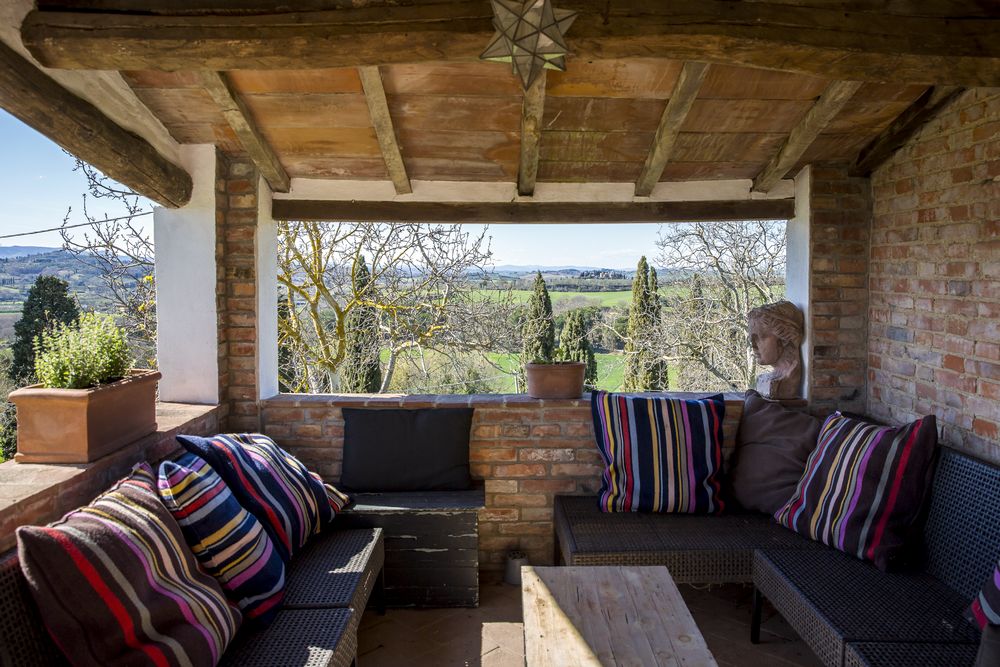 The covered terrace: low sofas, kilim cushions, the valley beyond the open arches
